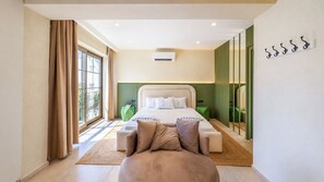 A modern bedroom with a large bed, a seating area, and a view through a window. - Luz Suit (Kaş)