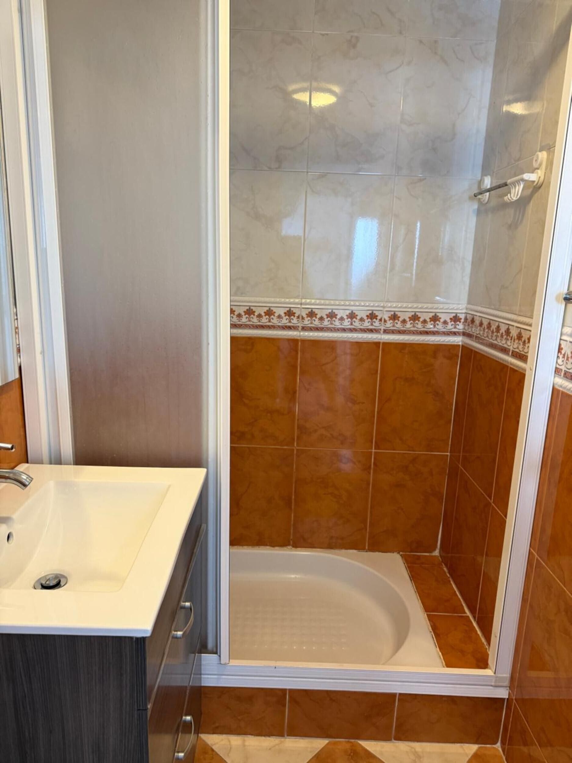 A bathroom with a sink, a shower, and a toilet.