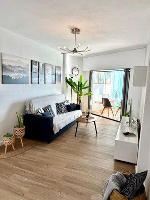 A modern living room with a sofa, coffee table, and potted plants. - Sea View Apartment with Pool in Almería for up to 4 Guests (Retamar)