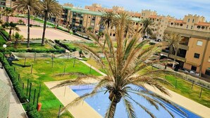 A resort with a swimming pool, palm trees, and modern buildings. - Sea View Apartment with Pool in Almería for up to 4 Guests (Retamar)
