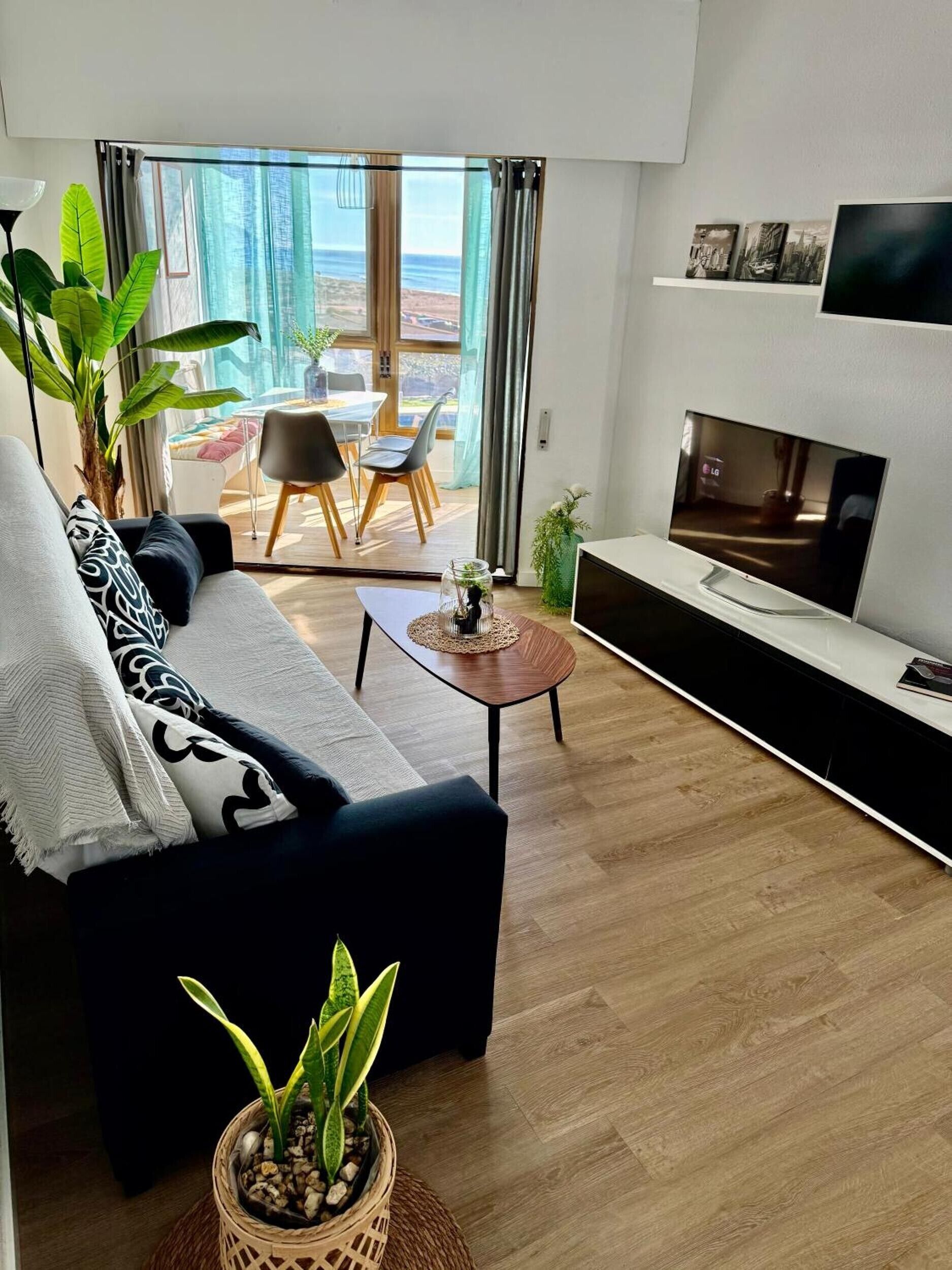 Una sala de estar moderna con sofá, mesa de centro, televisor y un comedor con sillas y mesa.