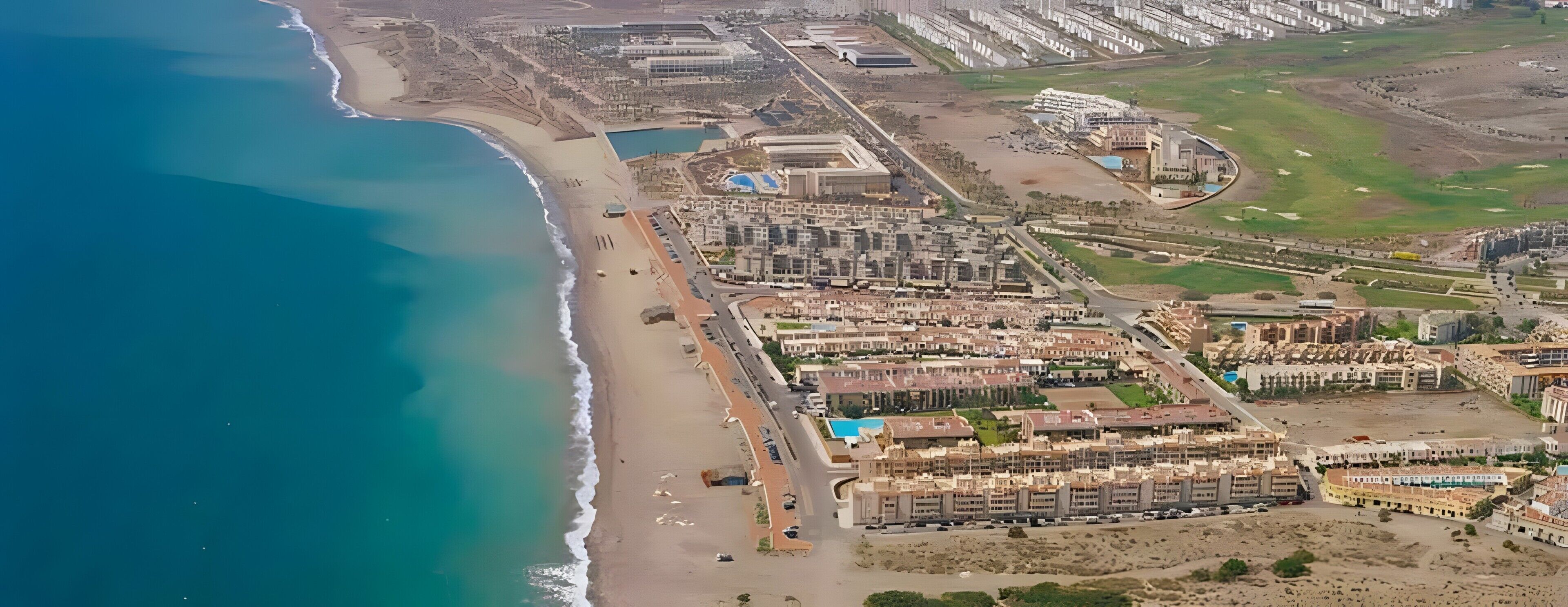 Luftaufnahme eines Küstenresorts mit Strandhäusern, einer Marina und einem Golfplatz.