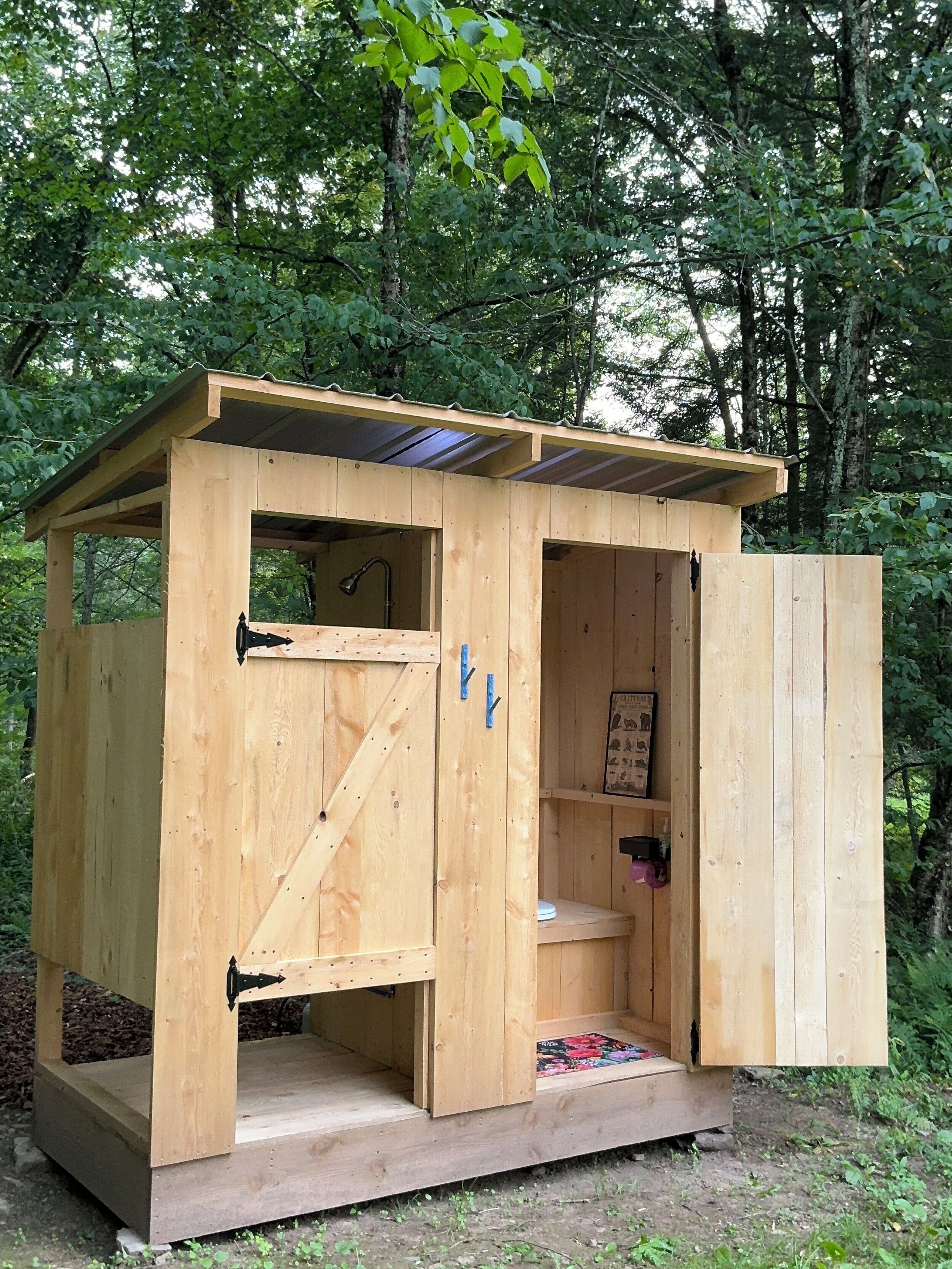 A wooden cabin with a door open, revealing a toilet and a shelf with items.