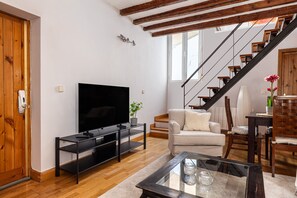 A living room with a TV, sofa, coffee table, and staircase. - Waou Sol X - Short-Term Rental (Madrid)