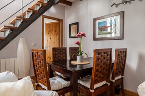 Ein Essbereich mit einem Holztisch, Stühlen, einer Vase mit Blumen und einer Treppe.