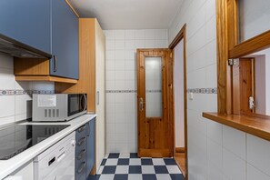 A compact kitchen with a microwave, oven, and dishwasher. - Waou Sol X - Short-Term Rental (Madrid)