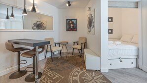 Ett modernt hotellrum med en matplats, en säng och konstverk på väggarna.