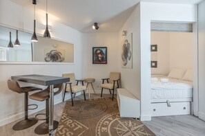 Ein modernes Hotelzimmer mit Essbereich, einem Bett und Kunstwerken an den Wänden.