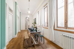 Ein langer Esstisch mit Stühlen, einer Bank und einem Fenster mit Vorhängen.