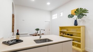 A modern kitchen with a central island, a built-in sink, and a yellow storage unit. - Waou Gran Via IX - Short-Term Rental (Madrid)