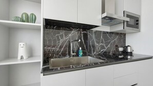 A modern kitchen with a black marble backsplash, stainless steel sink, and white cabinetry. - Apartment 'U Gnore - Polpo Room' with Sea View, Wi-Fi and Air Conditioning (Bari)