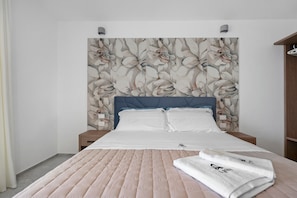 A bedroom with a bed, a headboard with floral wallpaper, a bedside table, and a folded towel on the bed. - Apartment 'U Gnore - Polpo Room' with Sea View, Wi-Fi and Air Conditioning (Bari)