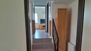 Een trap die leidt naar een kamer met een radiator, een houten kast en uitzicht op een andere kamer met een radiator en een klok.