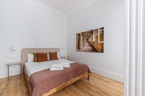 A bedroom with a bed, a bedside table, a wall-mounted lamp, and a painting. - Waou Sol XI - Short-Term Rental (Madrid)