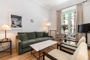 A modern living room with a green sofa, a small table, a lamp, and a TV. - Waou Sol XI - Short-Term Rental (Madrid)