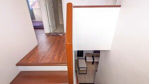 Un escalier avec des marches en bois et une rampe, menant à une pièce comprenant un lit et une fenêtre.