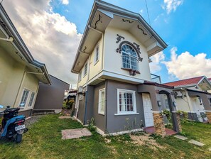 Une maison à deux étages avec un balcon, un garage et un petit jardin.