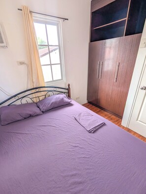 A bedroom with a bed, a window with curtains, a wardrobe, and a door. - Panglao 4 Bedroom Family and Group House With Pool (Panglao)