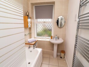 Une salle de bain avec une baignoire, un lavabo et une fenêtre.