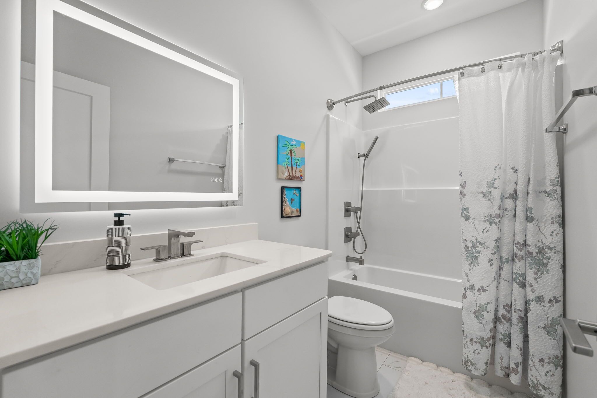 A modern bathroom with a large mirror, a sink, a toilet, and a shower.