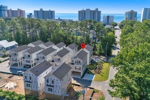 A residential complex with multiple two-story buildings, a clear view of the ocean, and a road leading to the beach. - Beachfront Luxury Apartment w/ Free Parking & (Myrtle Beach)