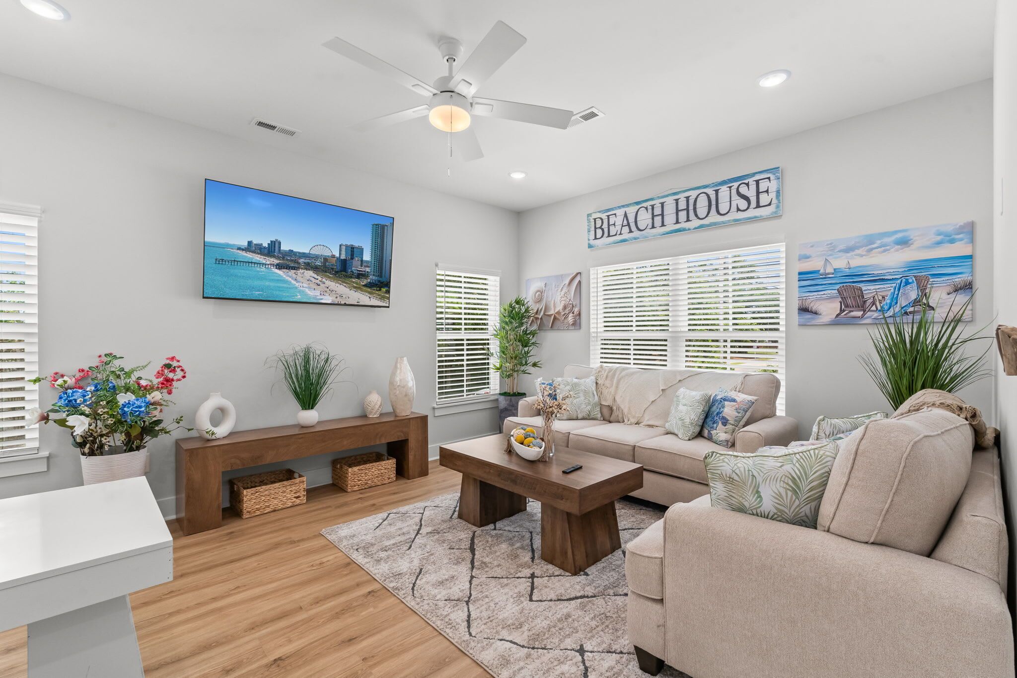 A living room with a sofa, coffee table, and a TV displaying a beach scene.