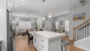 A modern kitchen with a large island, white cabinetry, and pendant lighting.