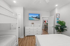 A bedroom with bunk beds, a dresser, a television, and a large plant. - Beachfront Luxury Apartment w/ Free Parking & (Myrtle Beach)