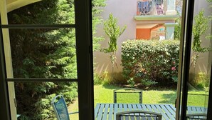 Une porte-fenêtre coulissante donne sur un espace patio extérieur aménagé avec une table et des chaises.