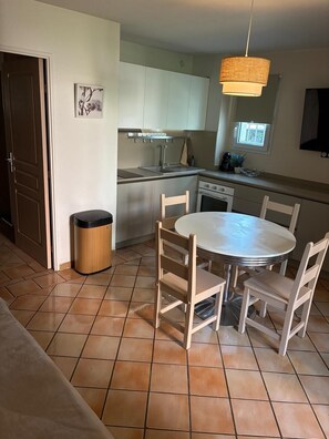 A compact kitchen with a dining area, a trash bin, and a window. - Beautiful, air-conditioned one-bedroom apartment with a fully equipped kitchen, sleeps 6, with a pool (Grimaud)