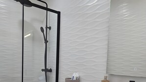 A modern bathroom with a glass shower enclosure, a white toilet, a wooden vanity, and a mirror above the sink. - Casa da Lota: House with Large Terrace, Sea and Lota View (Vieira de Leiria)