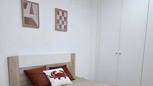 A bedroom with a bed, a wardrobe, and two framed artworks on the wall. - Casa da Lota: House with Large Terrace, Sea and Lota View (Vieira de Leiria)