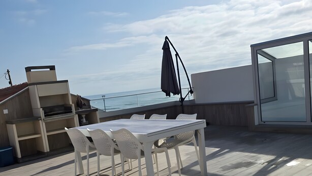A rooftop terrace with a table and chairs, a grill, and a view of the sea. - Casa da Lota: House with Large Terrace, Sea and Lota View (Vieira de Leiria)