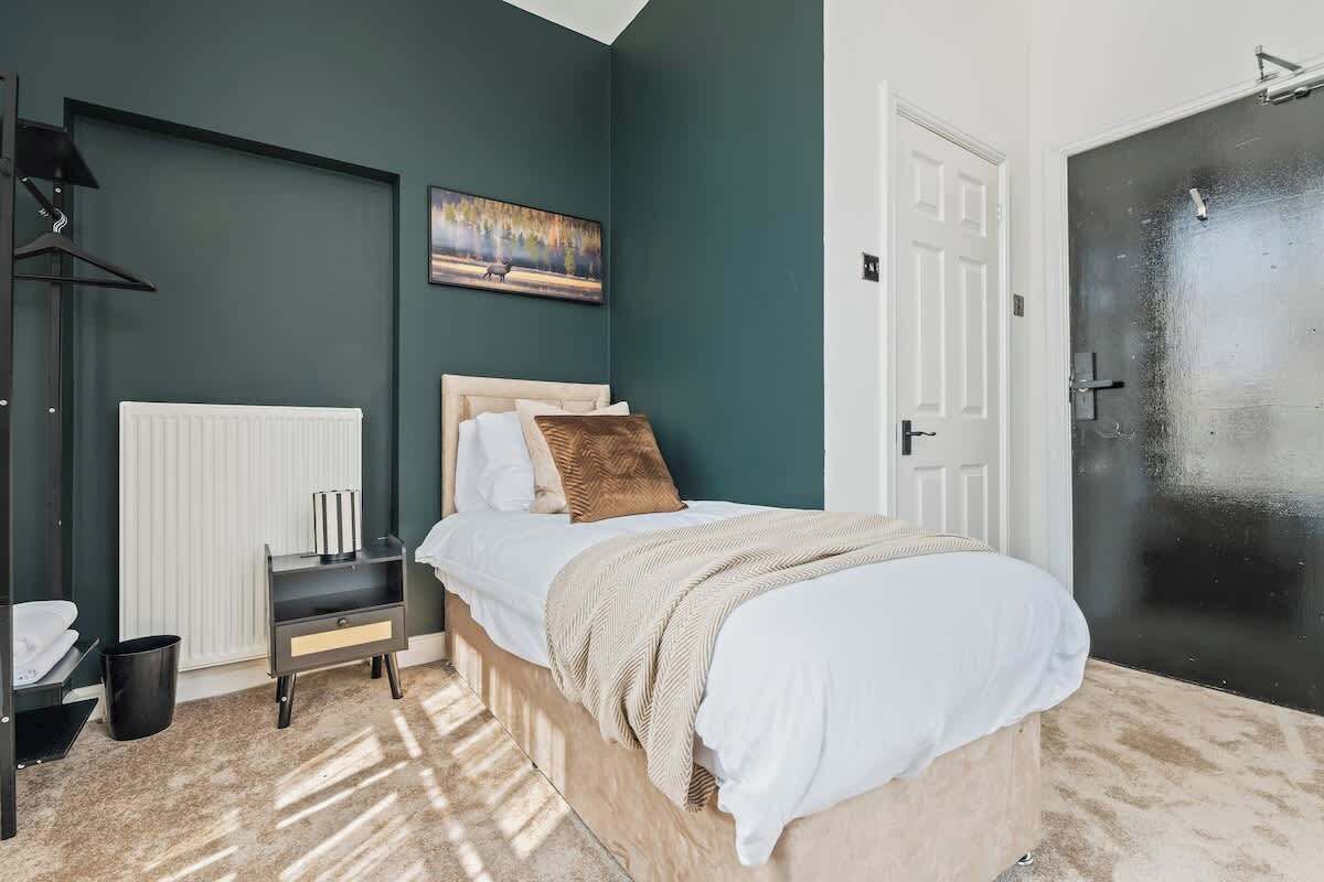 Ein Schlafzimmer mit Bett, Nachttisch, Heizkörper und einer Tür.