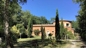 Un edificio con techo curvo, rodeado de árboles y un césped.