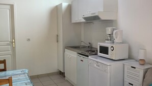 Cocina compacta con microondas, cafetera y lavabo.