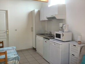 Eine kleine Küche mit Mikrowelle, Kaffeemaschine und Spüle.