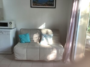 A room with a sofa, a microwave, and a painting on the wall. - Quiet studio in a garden and forest setting (Grayan-et-l'Hôpital)