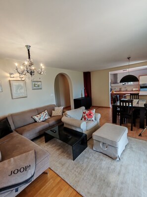 A living room with a sofa, ottoman, and coffee table, a chandelier, and a kitchen area visible through an archway. - Exclusive Retreat Villa Split - Heated pool with Hydrolysis system (no chlorine) (Solin)
