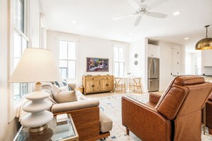 A modern living room with a sofa, coffee table, and a dining area with chairs. - The Lamar Landing, Pool+PB Court Velvet Ditch Villas (Oxford)