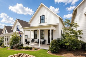 A two-story house with a covered porch, a flag, and a well-maintained lawn. - The Lamar Landing, Pool+PB Court Velvet Ditch Villas (Oxford)