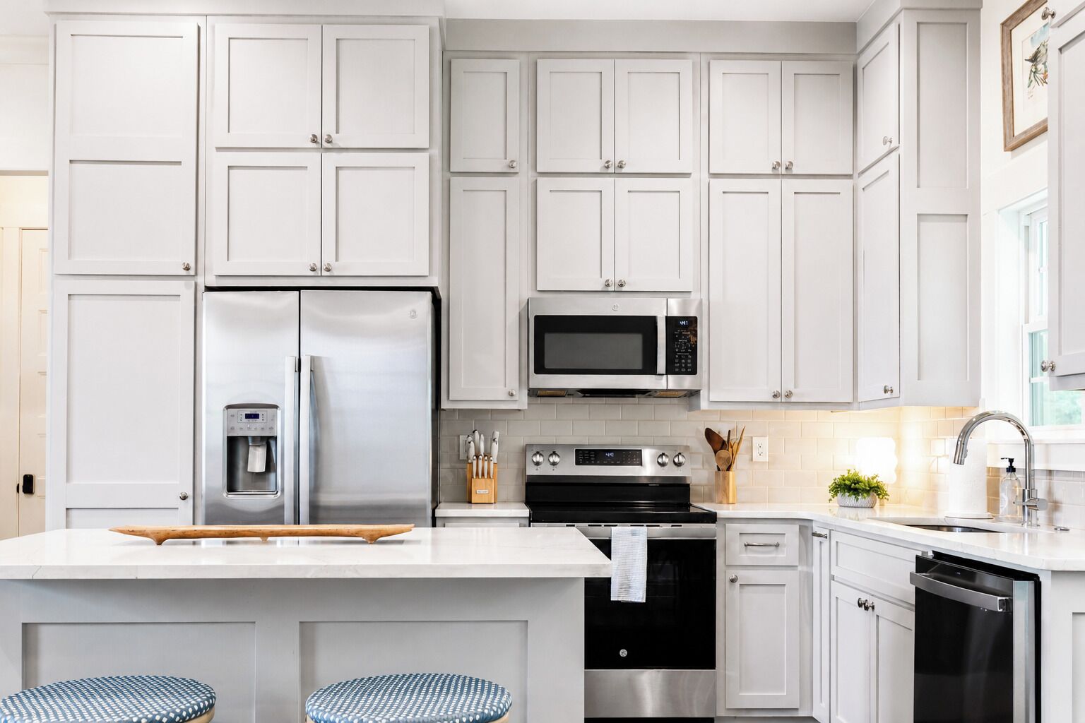 A modern kitchen with white cabinets, stainless steel appliances, and a central island with stools.