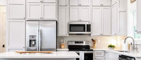 A modern kitchen with white cabinets, stainless steel appliances, and a central island with stools.