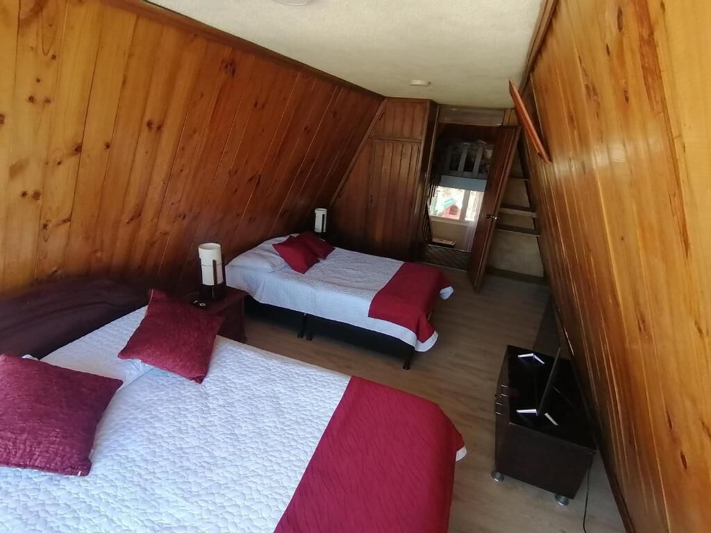 Une chambre avec deux lits, des murs en bois et une petite fenêtre.