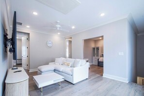 Ein modernes Wohnzimmer mit einem Ecksofa, einem Couchtisch und einem Deckenventilator.