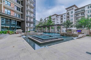 Un área de piscina moderna al aire libre con fuentes escalonadas y sillas de descanso.