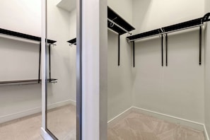 A closet with a mirrored door, a black shelf, and a metal rod for hanging clothes. - Luxury 3BR Penthouse |Skyline Views |Uptown Dallas (Dallas)