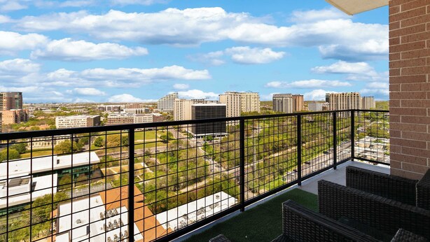 A balcony with a metal railing overlooking a cityscape with various buildings and a clear sky. - Luxury 3BR Penthouse |Skyline Views |Uptown Dallas (Dallas)