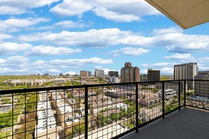 Ein Balkon mit Blick auf die Stadt, darunter hohe Gebäude und ein Parkplatz.