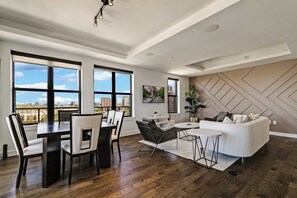 A modern living room with a dining area, large windows, and a city view. - Luxury 3BR Penthouse |Skyline Views |Uptown Dallas (Dallas)